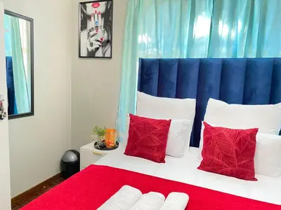 a bedroom with a large bed with red pillows at Ranx Guest House in Pretoria