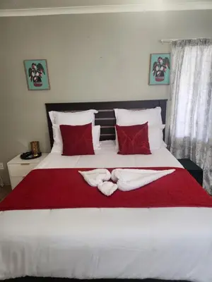 a bedroom with a large white bed with red pillows at Ranx Guest House in Pretoria