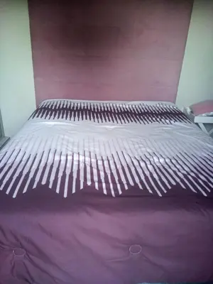 a bed in a bedroom with a purple bedspread at Solitary in Polokwane