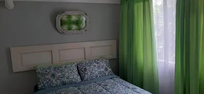 a bedroom with a bed and a window with green curtains at Villa at Wekker Upstairs in Pretoria