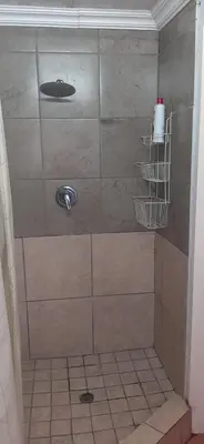 a shower in a bathroom with a tiled floor at Villa at Wekker Upstairs in Pretoria