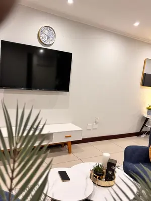 a living room with a large flat screen tv on the wall at Adilo Villa Midrand Hill of Good Hope 2 in Midrand