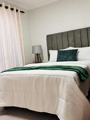 a bedroom with a large bed with a green and white blanket at Adilo Villa Midrand Hill of Good Hope 2 in Midrand