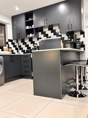 a kitchen with black cabinets and a counter with stools at Adilo Villa Midrand Hill of Good Hope 2 in Midrand