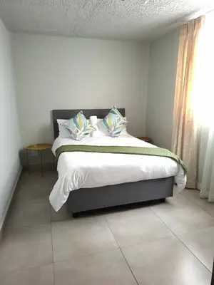 a bedroom with a bed with white sheets and pillows at Charcoal Suite- Circa Lynnwood in Pretoria