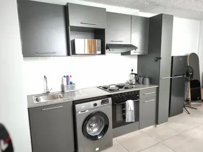 a kitchen with a washing machine and a sink at Charcoal Suite- Circa Lynnwood in Pretoria