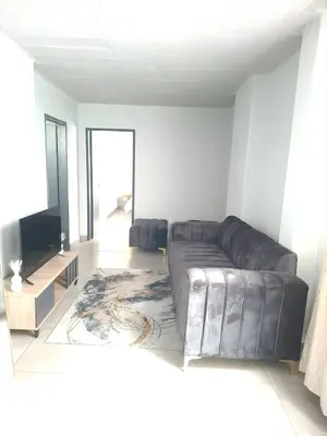 a living room with a leather couch and a television at Charcoal Suite- Circa Lynnwood in Pretoria