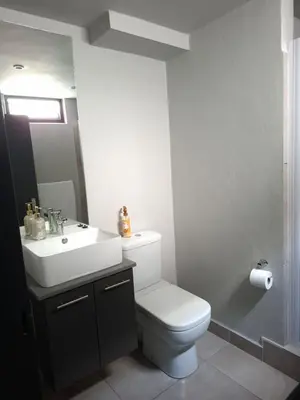 a bathroom with a white toilet and a sink at Charcoal Suite- Circa Lynnwood in Pretoria