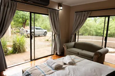 a bedroom with a bed and a couch and a window at Wonderviews Hedgehog in Marloth Park