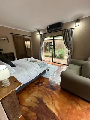 a bedroom with a bed and a couch and a window at Wonderviews Hedgehog in Marloth Park