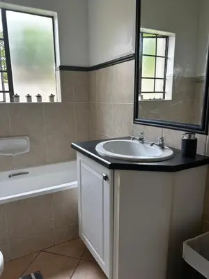 a bathroom with a sink and a mirror and a tub at 2 Bed Townhouse, Quiet and Stylish in Pretoria
