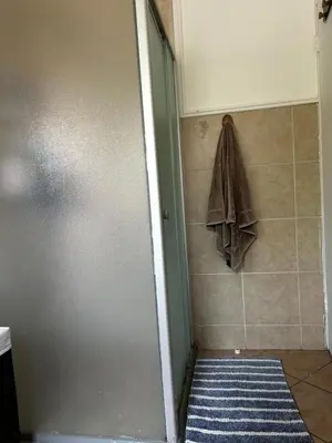 a bathroom with a shower with a towel on the wall at 2 Bed Townhouse, Quiet and Stylish in Pretoria