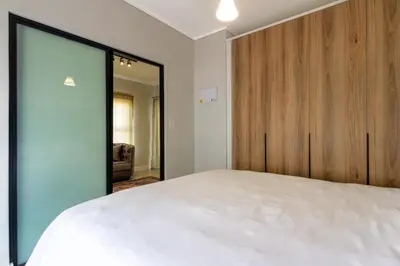 a bedroom with a white bed and a wooden cabinet at Stylish Modern 1 Bedroom in Midrand