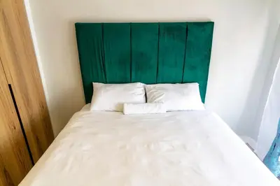 a bed with a green headboard and two white pillows at Stylish Modern 1 Bedroom in Midrand