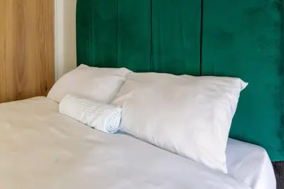 a bed with white pillows and a green headboard at Stylish Modern 1 Bedroom in Midrand