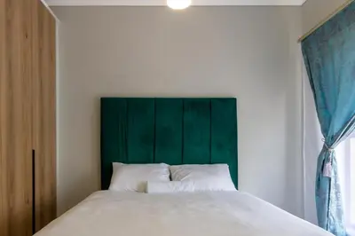 a bedroom with a large bed with a green headboard at Stylish Modern 1 Bedroom in Midrand