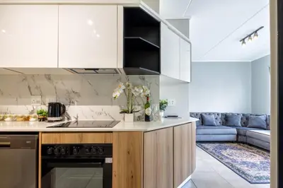 a kitchen with white cabinets and a couch at Stylish Modern 1 Bedroom in Midrand