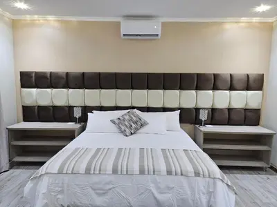 a bedroom with a large bed with a large headboard at Palms Erasmia in Centurion