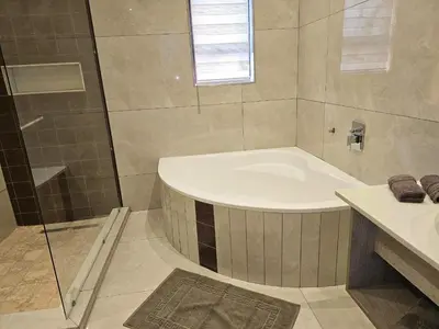 a bathroom with a tub and a shower and a sink at Palms Erasmia in Centurion
