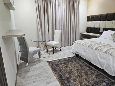 a bedroom with a bed and a table and chairs at Palms Erasmia in Centurion