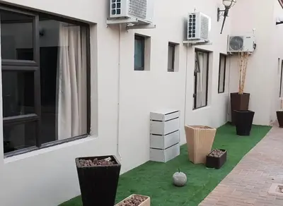 a white building with a green floor and windows at Palms Erasmia in Centurion