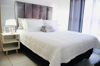 a bedroom with a large white bed with a teddy bear on it at The Blyde Crystal Lagoon Exclusive Apartment in Pretoria