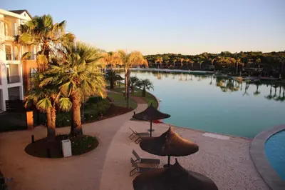 a pool with umbrellas and chairs next to a building at The Blyde Crystal Lagoon Exclusive Apartment in Pretoria