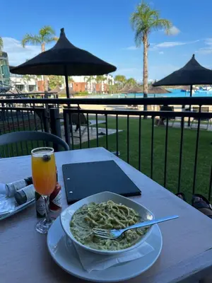 a plate of pasta on a table with a glass of orange juice at The Blyde Crystal Lagoon Exclusive Apartment in Pretoria