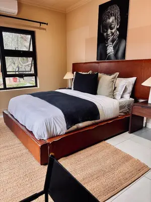 a large bed with a wooden headboard in a bedroom at Rhula Villa in Hoedspruit