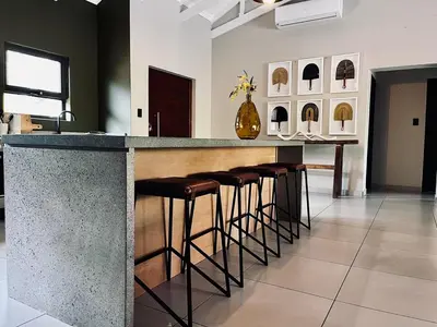 a bar with a row of stools in a room at Rhula Villa in Hoedspruit