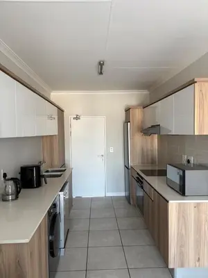 a kitchen with white counters and wooden cabinets at The Modern Stay At The Blyde in Pretoria