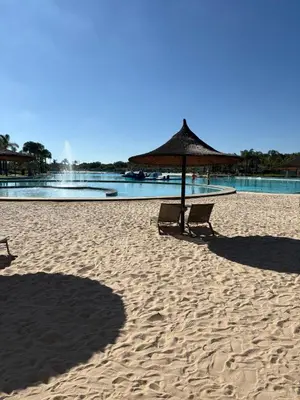 a beach with two chairs and an umbrella on the sand at The Modern Stay At The Blyde in Pretoria