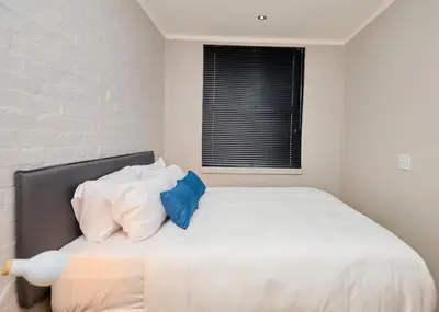a bedroom with a white bed with blue pillows at Brooklyn Modern Apartment Near Hatfield & Menlyn in Pretoria