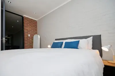 a bedroom with a large white bed with blue pillows at Brooklyn Modern Apartment Near Hatfield & Menlyn in Pretoria