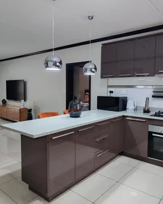 a kitchen with brown cabinets and a white counter top at Walford Prestige Apartment - by Global Links Properties in Midrand