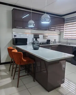a kitchen with a large counter and two chairs at Walford Prestige Apartment - by Global Links Properties in Midrand