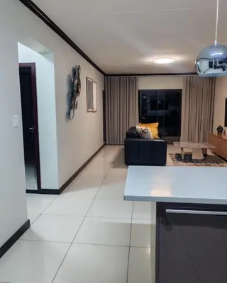 a kitchen and living room with a couch in the background at Walford Prestige Apartment - by Global Links Properties in Midrand