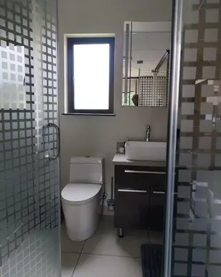 a bathroom with a toilet and a sink and a window at Walford Prestige Apartment - by Global Links Properties in Midrand