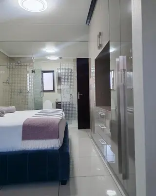 a bedroom with a bed and a walk in shower at Walford Prestige Apartment - by Global Links Properties in Midrand