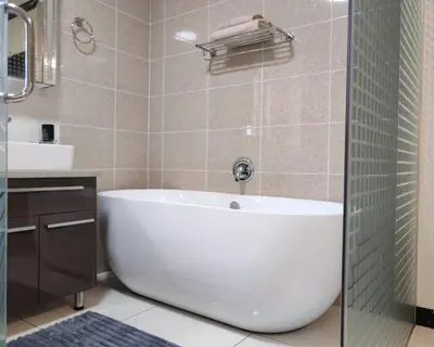 a bathroom with a white tub and a sink at Walford Prestige Apartment - by Global Links Properties in Midrand