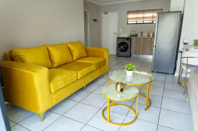 a living room with a yellow couch and tables at GreenPark Home A chic retreat and peaceful home in Boksburg