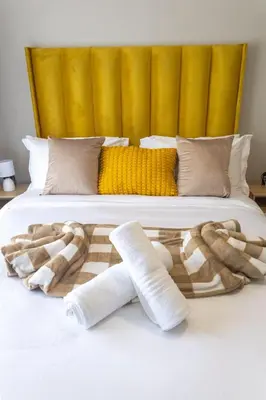 a bed with two wrapped towels on it at GreenPark Home A chic retreat and peaceful home in Boksburg