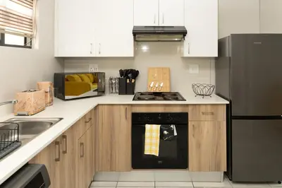 a kitchen with white cabinets and a black oven at GreenPark Home A chic retreat and peaceful home in Boksburg