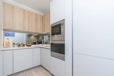 a kitchen with white cabinets and stainless steel appliances at Elegant AirConditioned Neria at Ellipse Waterfall in Midrand
