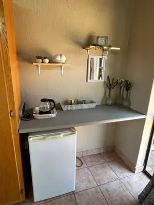 a small kitchen with a counter and a refrigerator at Dorpsrus in Bela-Bela