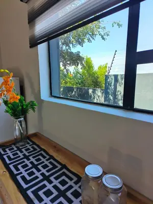 a window with three jars on a table with a vase at the Host at Bingos House in Thohoyandou