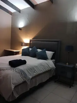a bedroom with a large bed with blue pillows at the Host at Bingos House in Thohoyandou