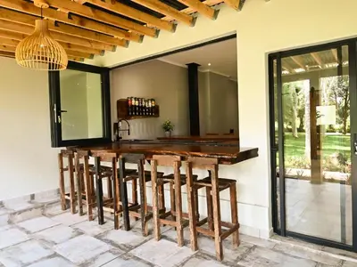 an outdoor kitchen with a wooden bar with stools at The Roaming Goat Guesthouse in Toekoms