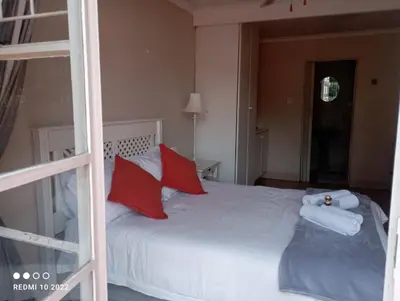 a bedroom with a white bed with red pillows at Bloemhoek Guest House in Centurion