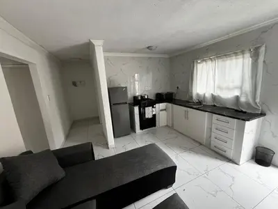 a living room with a couch and a kitchen at Sunset Rest Guesthouse in Secunda